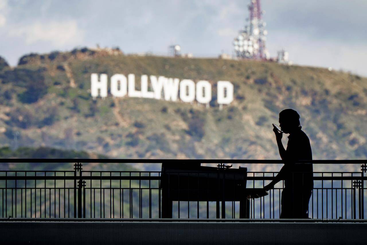 FILE - A worker wheels equipment past the famous Hollywood sign as preparations continue on March 8, 2023, for the 95th Academy Awards at the Dolby Theatre in Los Angeles. Television and movie writers declared late Monday, May 1, that they will launch an industrywide strike for the first time in 15 years, as Hollywood girded for a walkout with potentially widespread ramifications in a fight over fair pay in the streaming era. (AP Photo/J. David Ake, File)