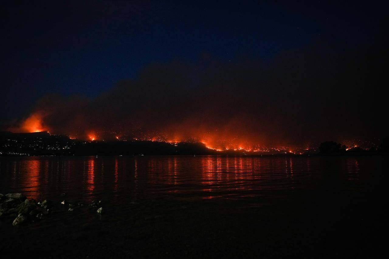 The McDougall Creek wildfire burns on the mountainside above lakefront homes in West Kelowna, B.C., on Friday, Aug. 18, 2023. West Kelowna area residents are being warned to stay out of wildfire restricted areas or face possible fines. THE CANADIAN PRESS/Darryl Dyck