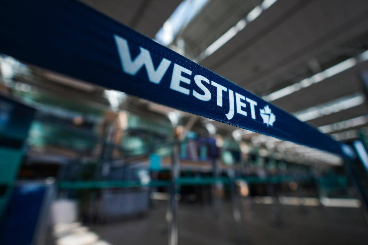 A WestJet logo is seen in the domestic check-in area at Vancouver International Airport, in Richmond, B.C., on Friday, May 19, 2023.The union representing WestJet cabin crew is demanding an apology from the airline after Conservative Leader Pierre Poilievre delivered a speech on the public address system of a recent flight. THE CANADIAN PRESS/Darryl Dyck