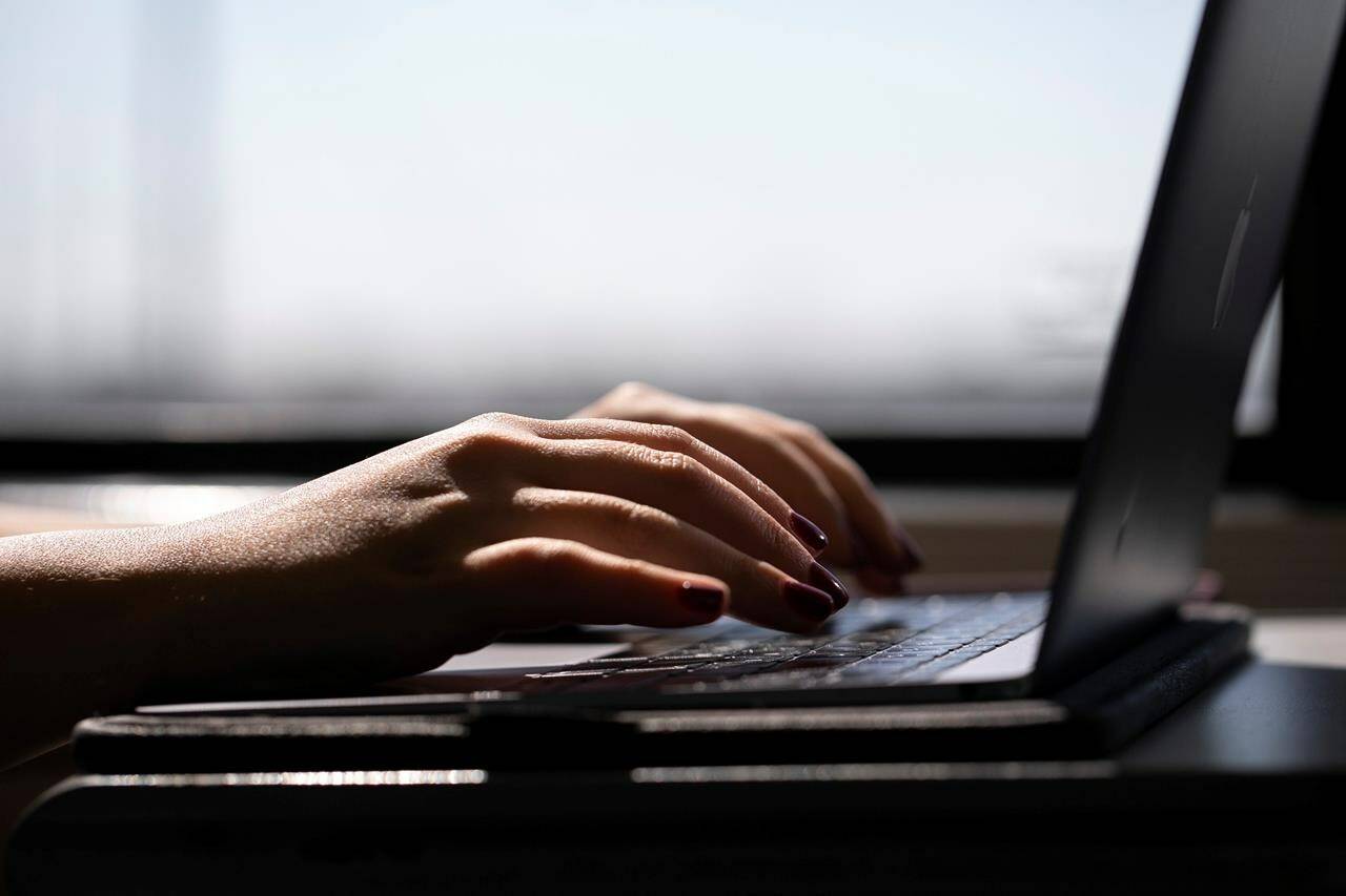 A woman types on a laptop on a train in New Jersey on May 18, 2021. The Weather Network and MétéoMédia still can’t send weather alerts through push notifications from its app following a “malicious cyberattack” on Monday. THE CANADIAN PRESS/AP, Jenny Kane