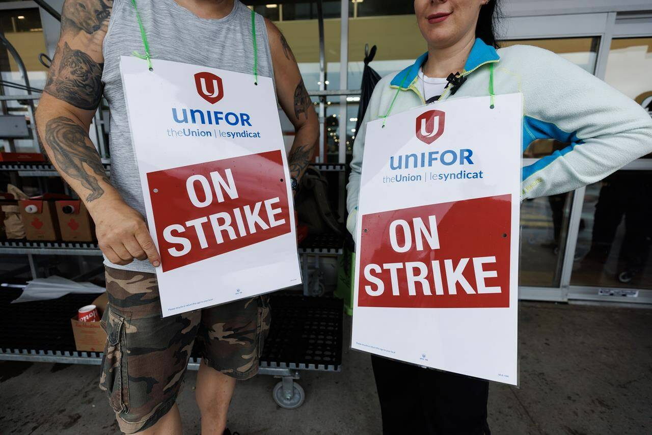 Workers hold signs at a picket line outside a Metro grocery store in Toronto as workers rejected a tentative deal triggering a strike of nearly 3,700 grocery store workers in the Greater Toronto Area, Saturday, July 29, 2023. It was Samantha Henry’s first time on strike, and one that made headlines across the country. THE CANADIAN PRESS/Cole Burston