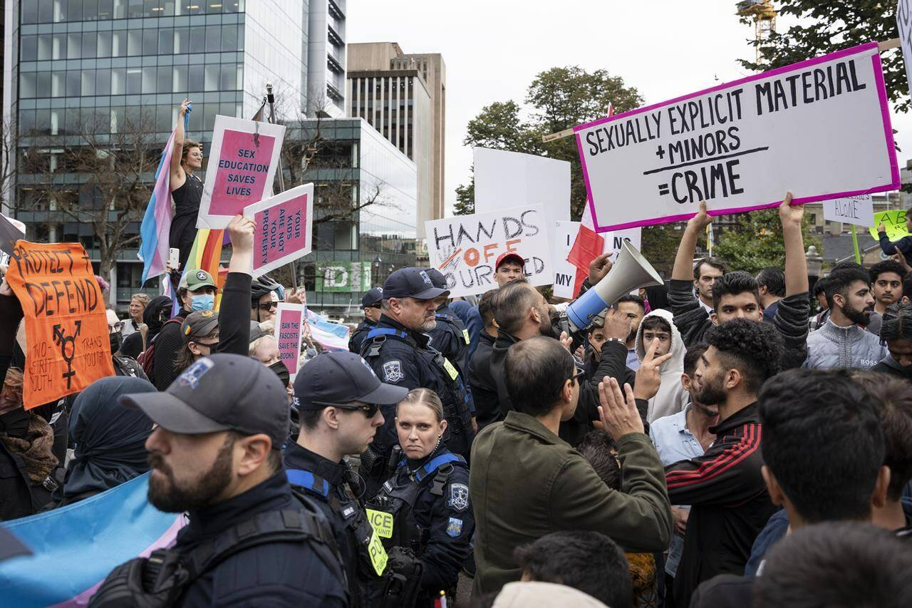 Police stand between protesters opposed to gender diversity in schools, right, and counter-protesters advocating for trans rights, left, in Halifax on Wednesday, September 20, 2023. Protests and counter-protests for and against Canada’s trans and 2SLGBTQIA+ community were planned across Canada by “1MillionMarch4Children” who are against so-called “gender ideology” being taught in schools. THE CANADIAN PRESS/Darren Calabrese