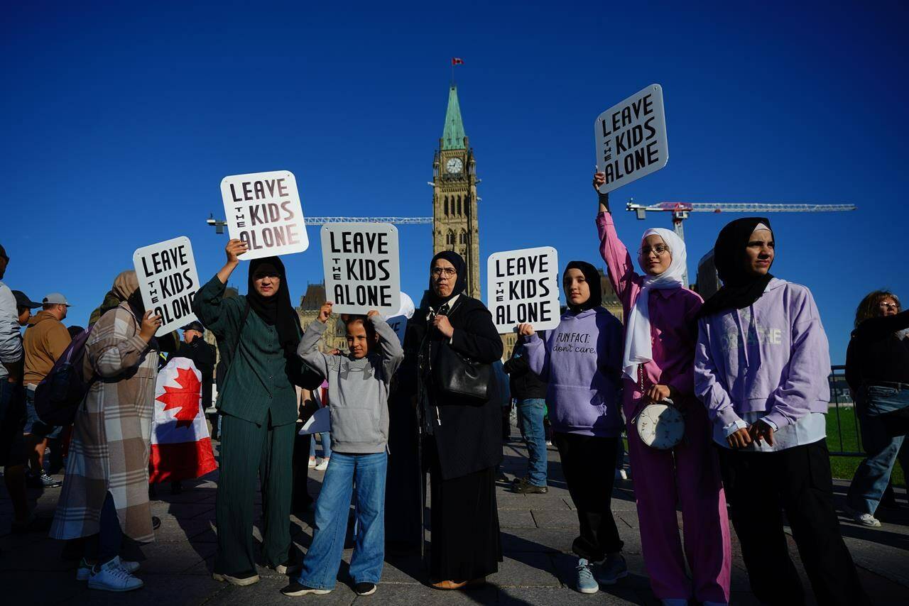 People hold signs during a demonstration on Parliament Hill in Ottawa on Wednesday, Sept. 20, 2023. Protests and counter-protests for and against Canada’s trans and LGBTQ community are being planned across Canada on Wednesday. THE CANADIAN PRESS/Sean Kilpatrick
