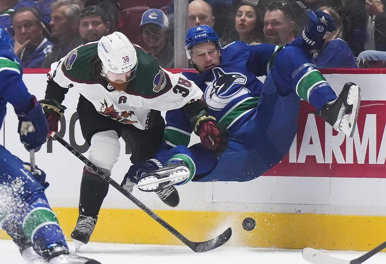 Vancouver Canucks’ defenceman Tucker Poolman, right, is upended by Arizona Coyotes’ Liam O’Brien (38) during the first period of a pre-season NHL hockey game in Vancouver, on Friday, October 7, 2022. Poolman will start the upcoming NHL season on long-term injured reserve as he continues to recover from migraines.THE CANADIAN PRESS/Darryl Dyck