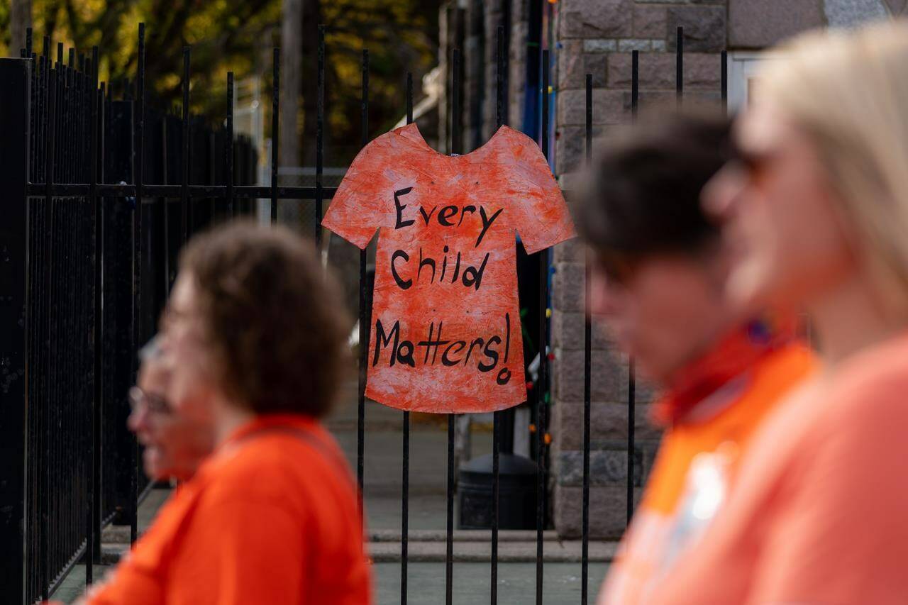 A sign of an orange shirt is attached to a fence during a Truth and Reconciliation walk in Saskatoon, Sask., on Friday, September 30, 2022. THE CANADIAN PRESS/Heywood Yu