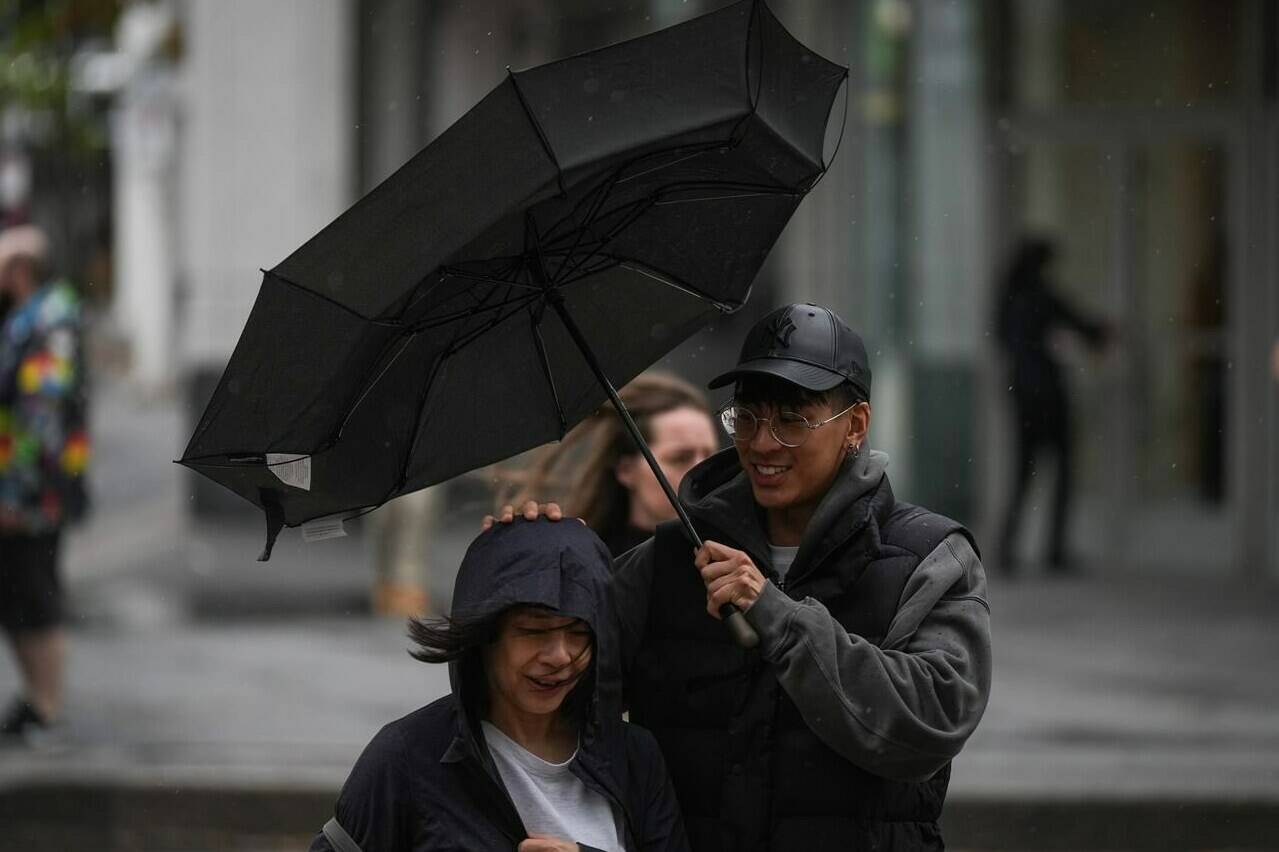 A man struggles with an umbrella in the wind as rain falls in Vancouver, on Monday, Sept. 25, 2023. THE CANADIAN PRESS/Darryl Dyck