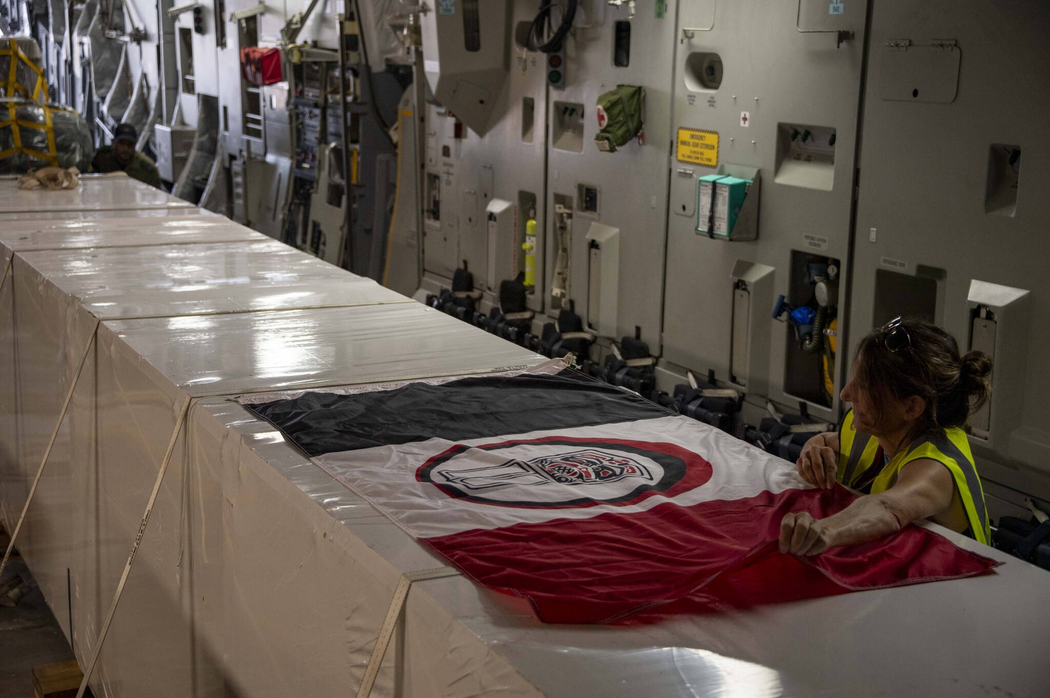 The Nisg̱a’a Nation’s flag is laid across the exterior of the custom-built crate that houses the House of Ni’isjoohl Memorial Pole onto a plane in the United Kingdom on Sept. 14. (Master Corporal Nicolas Alonso, Canadian Armed Forces, via House of Ni’isjoohl/Nisg̱a’a Lisims Government)