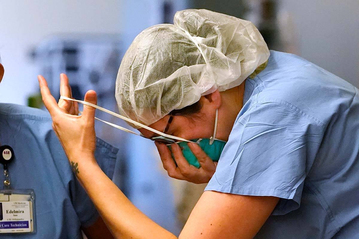 A registered nurse pulls on an N-95 mask in a COVID Acute Care Unit in Seattle, Washington. (AP Photo/Elaine Thompson)