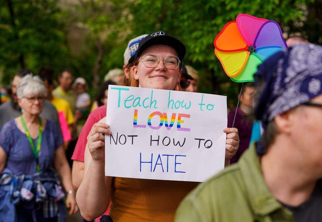 A person holds a sign during a pride rally in Saskatoon on Thursday, June 1, 2023. A Saskatchewan judge has granted an injunction over a government policy that requires parental consent when children under 16 want to go by different names and pronouns at school. THE CANADIAN PRESS/Heywood Yu