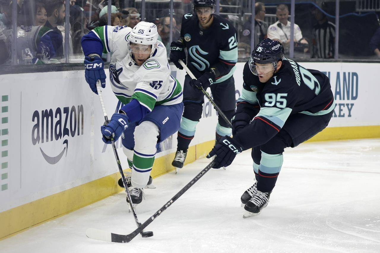 Vancouver Canucks defenceman Guillaume Brisebois (55) and Seattle Kraken left wing Andre Burakovsky (95) battle for the puck during the first period of an NHL hockey preseason game, Thursday, Sept. 28, 2023, in Seattle. (AP Photo/John Froschauer)