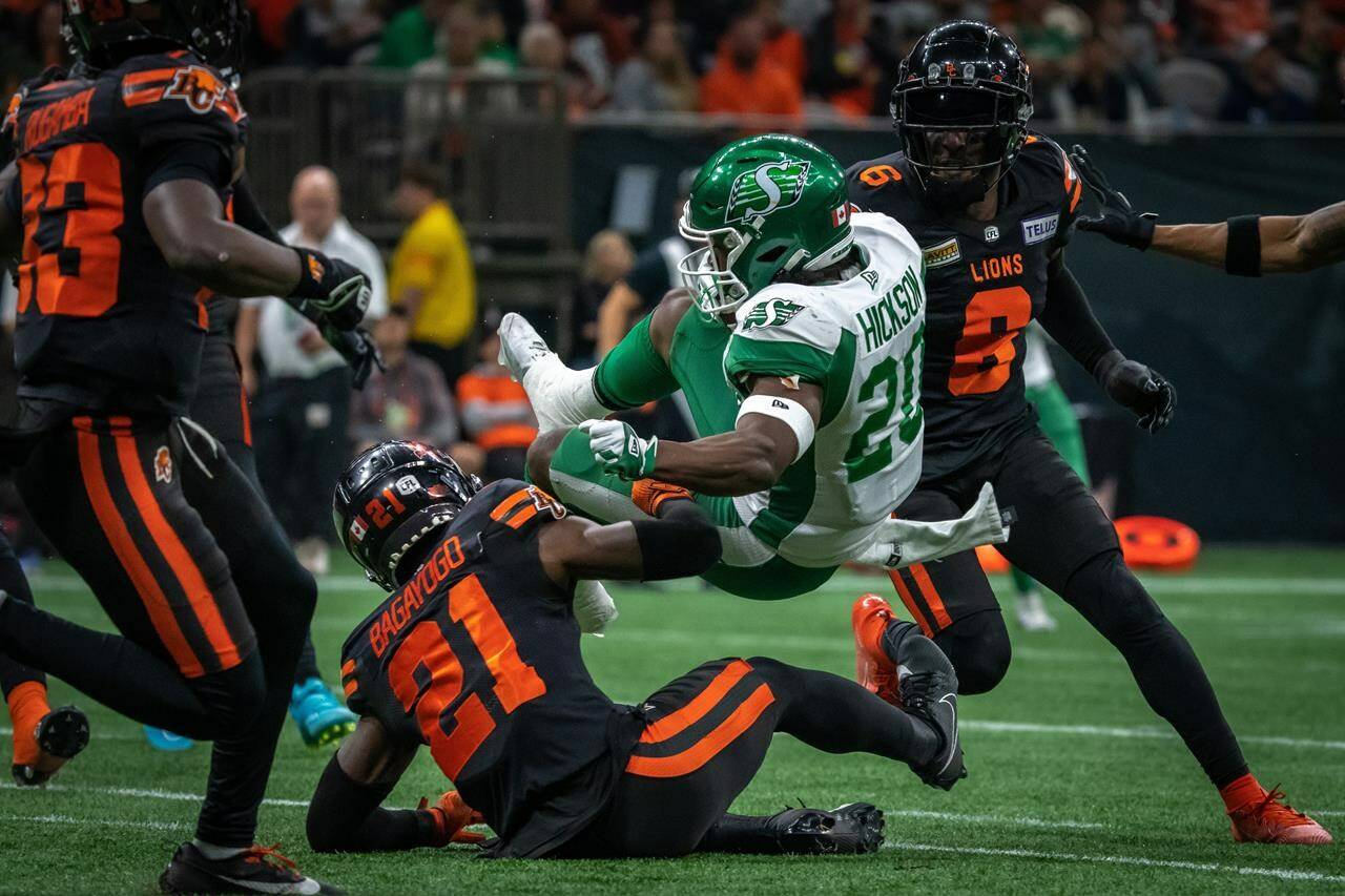 Saskatchewan Roughriders running back Frankie Hickson (20) is tackled by B.C. Lions’ Siriman Harrison Bagayogo (21) during first half of CFL football action in Vancouver, B.C., Friday, Sept. 29, 2023. THE CANADIAN PRESS/Ethan Cairns