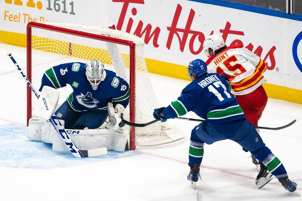 Vancouver Canucks goaltender Thatcher Demko (35) stops Calgary Flames’ Dryden Hunt (15) as Canucks’ Filip Hronek (17) defends during the first period of an NHL preseason hockey game in Vancouver on Friday, October 6, 2023. THE CANADIAN PRESS/Ethan Cairns