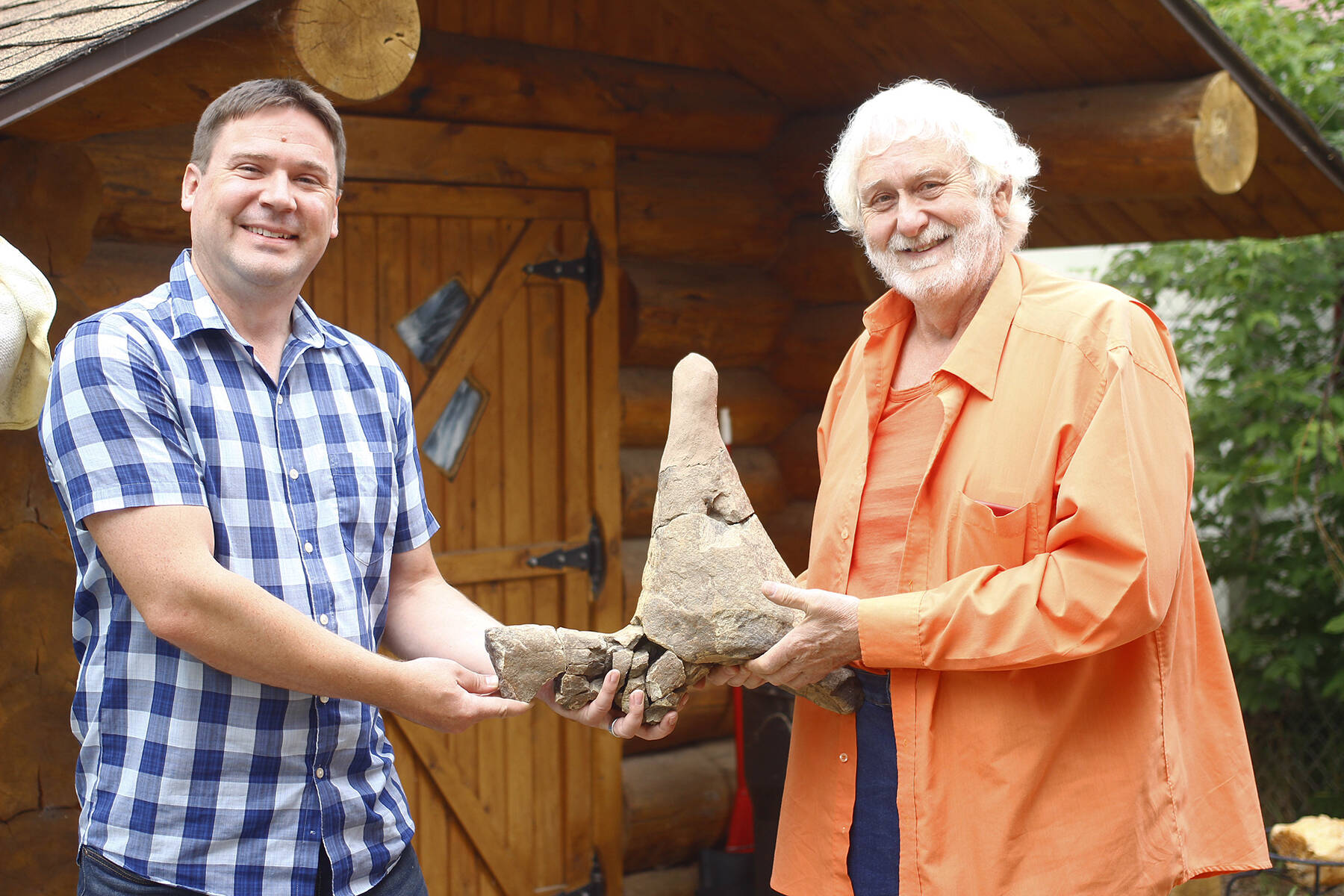 Dr. Caleb Brown, left and Garry McCue hold the piece of Triceratops horn being donated to the Royal Tyrrell Museum. Note: Image was altered to remove location-identifying information. (Photos by Emily Jaycox/Ponoka News)