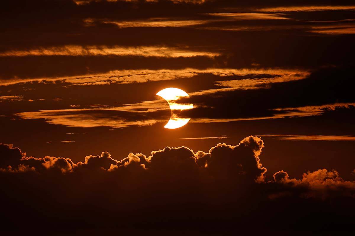 A partial solar eclipse rises behind clouds, Thursday, June 10, 2021, in Arbutus, Maryland, U.S. The 2023 solar eclipse will be visible in B.C. on Saturday, Oct. 14 morning. (AP Photo/Julio Cortez)