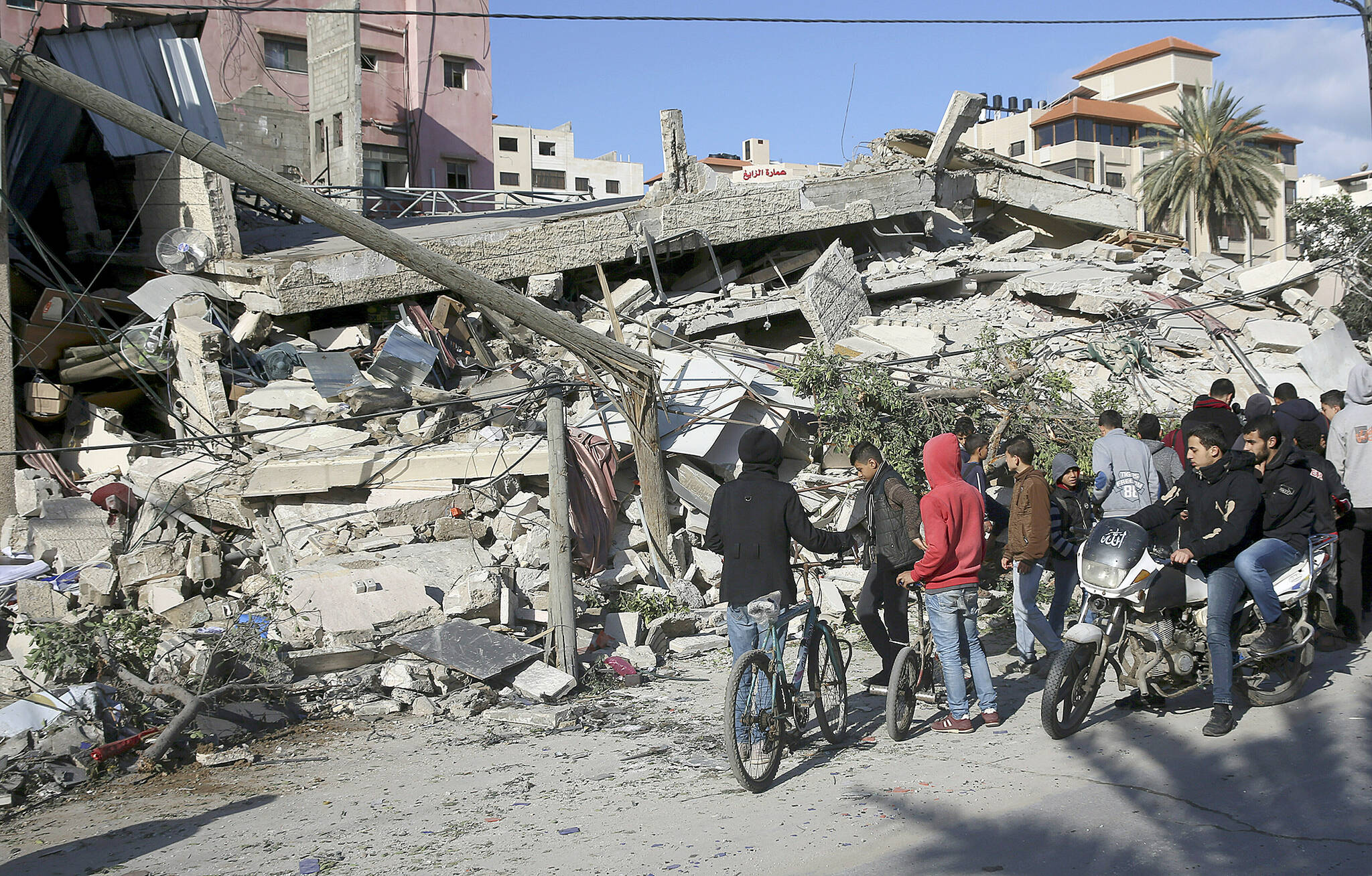 Residents inspect the damage of the destroyed multi-story building of Hamas-affiliated insurance company, in Gaza City, Tuesday, March 26, 2019. A tense quiet took hold Tuesday morning after a night of heavy fire as Israeli aircraft bombed targets across the Gaza Strip and Gaza militants fired rockets into Israel in what threatened to devolve into a major conflict two weeks before the Israeli election. (AP Photo/Adel Hana)