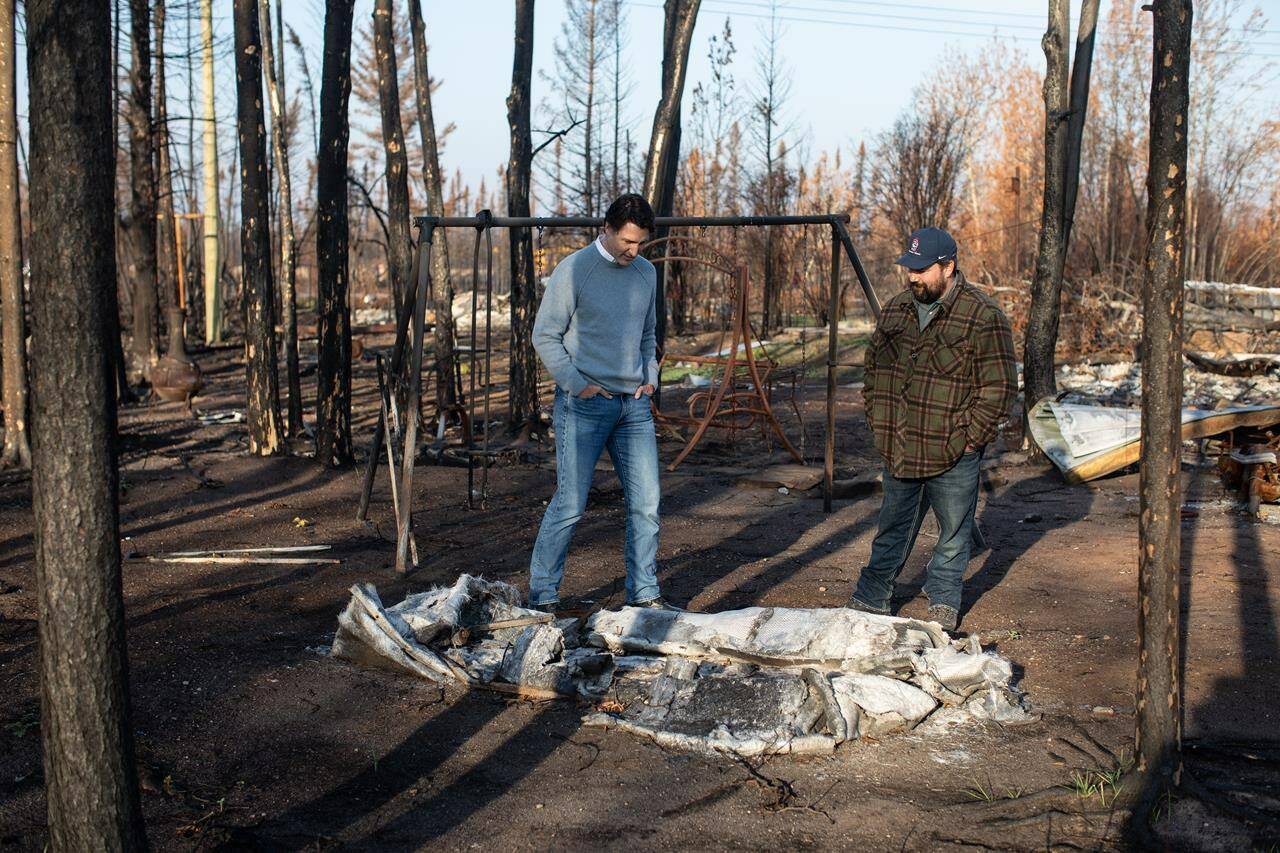 Prime Minister Justin Trudeau, left, tours Chaal Cadieux’s devastated property from the wildfire in Enterprise, Northwest Territories on Wednesday, October 11, 2023. THE CANADIAN PRESS/Jason Franson
