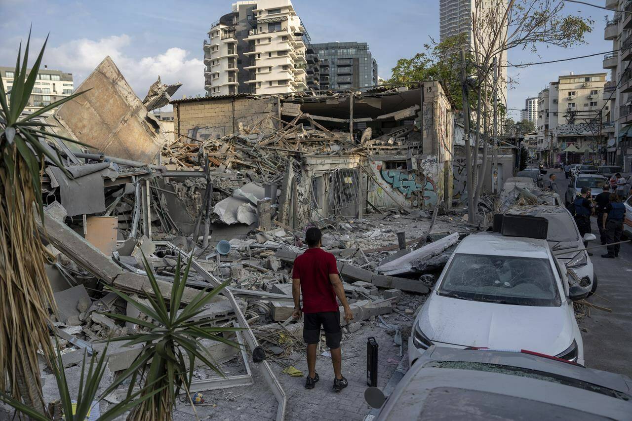 Israelis inspect the rubble of a building a day after it was hit by a rocket fired from the Gaza Strip, in Tel Aviv, Israel, Sunday, Oct. 8, 2023. THE CANADIAN PRESS/AP-Oded Balilty