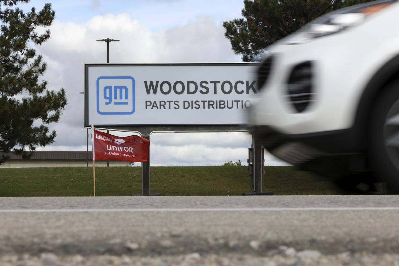 A Unifor flag waves in the wind in front of the sign at the Woodstock Parts Distribution Centre, in Woodstock, Ont., on Tuesday, Oct. 10, 2023. THE CANADIAN PRESS/Nicole Osborne