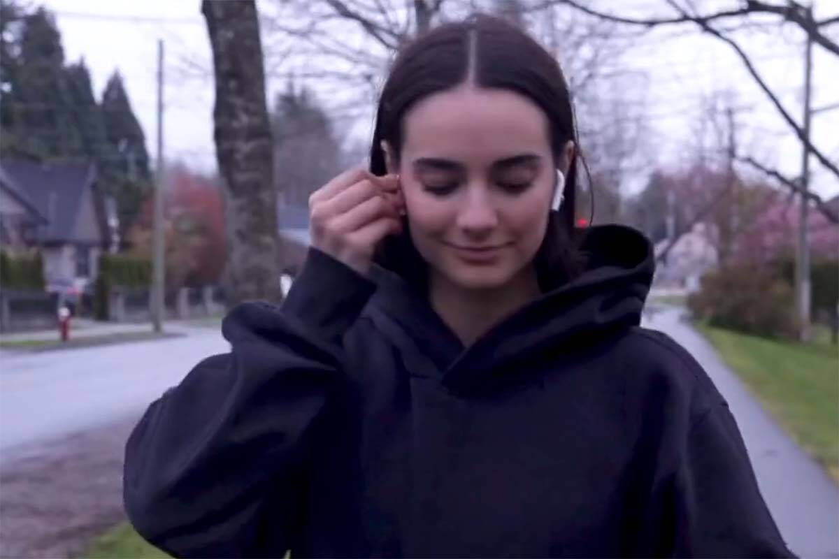 A screenshot taken from a pedestrian safety video by Richmond RCMP shows a woman putting in ear buds before pulling up the hood of her hoodie. In the posting of the video, the detachment said pedestrian safety is “a two-way street,” drawing online ire. (Screenshot/@RichmondRCMP/X)