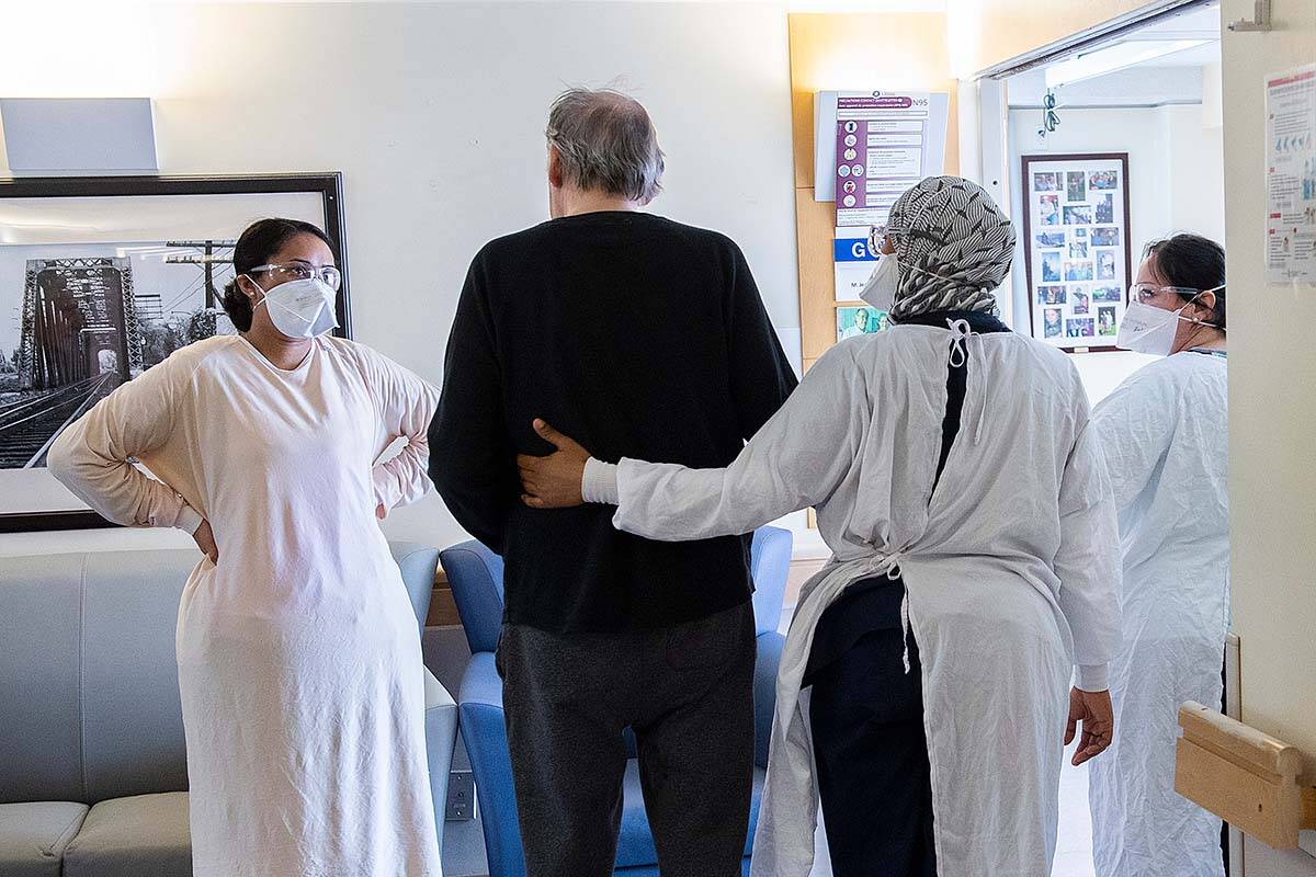 Health-care workers talk with a man in a COVID-19 infected ward at Idola Saint-Jean long-term care home in Laval, Que., Friday, February 25, 2022. In B.C., a September 2023 survey of health care assistants shows half of them are considering quitting in the next two years. THE CANADIAN PRESS/Graham Hughes