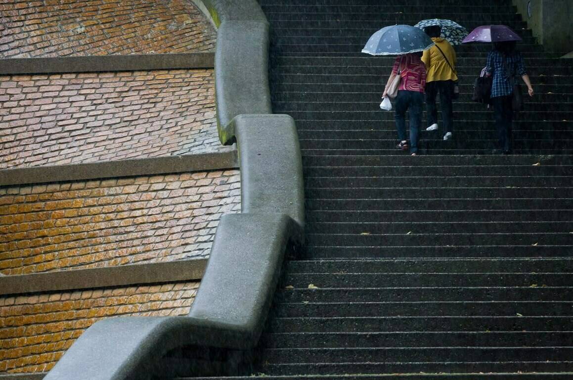Rainfall warnings across Vancouver Island and the inner south coast have lifted in most areas, but the effects of British Columbia’s first atmospheric river of autumn could take a little longer to ease. Women use umbrellas as they walk up steps during heavy rainfall in New Westminster, B.C., on Friday July 20, 2012. THE CANADIAN PRESS/Darryl Dyck