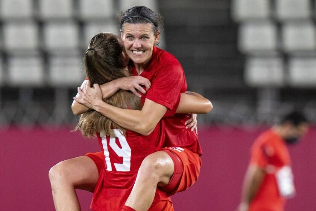 Canada forward Christine Sinclair (12) leaps into the arms of forward Jordyn Huitema (19) to celebrate their win in semifinal football action against the United States of America at the Tokyo Olympics in Kashima, Japan, Monday, Aug. 2, 2020. The star Canadian soccer player has announced her retirement. THE CANADIAN PRESS/ Frank Gunn