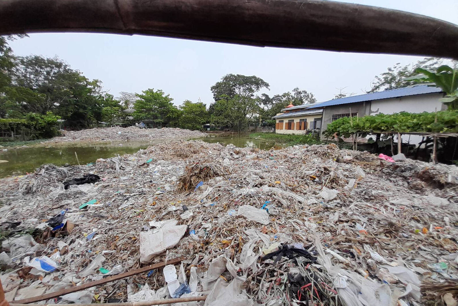 Trash, including large quantities of plastic waste, line a small pond behind a religious shelter in Shwepyithar, Myanmar, in an undated photo. THE CANADIAN PRESS/HO-Lighthouse Reports