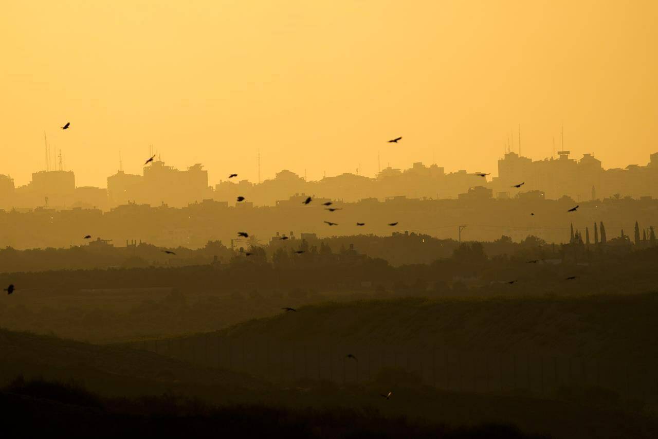 A flock of birds fly as the sun sets at the Gaza Strip, as seen from southern Israel, Friday, Oct. 20, 2023. (AP Photo/Francisco Seco)