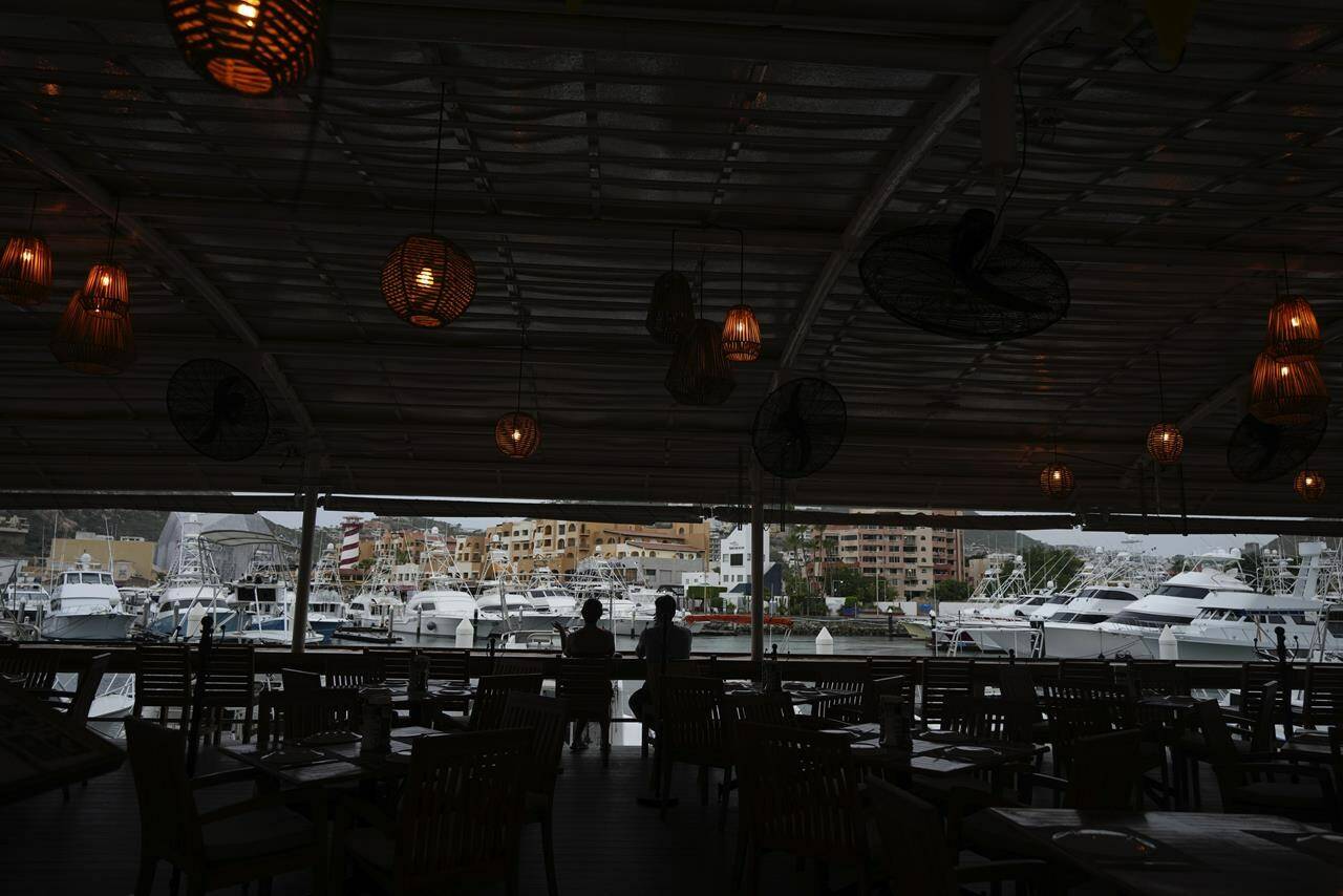 A couple tourists take a drink in a bar still open at the harbor of Cabo San Lucas, Mexico, Friday, Oct. 20, 2023. Hurricane Norma is heading for the resorts of Los Cabos at the southern tip of Mexico’s Baja California Peninsula, while Tammy grew into a hurricane in the Atlantic. (AP Photo/Fernando Llano)