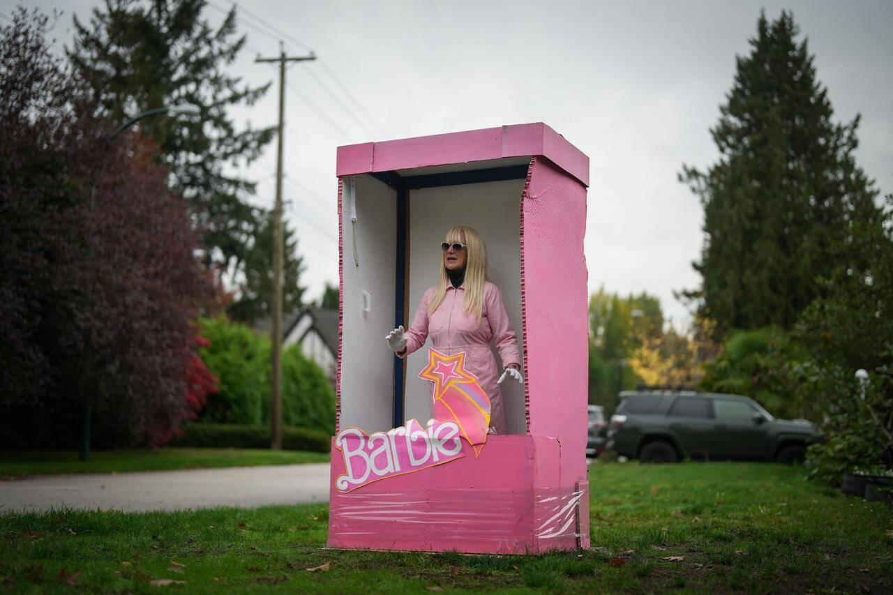 Anne Bruinn stands dressed as a Barbie doll inside a box in an attempt to entertain motorists driving past her home in Vancouver, on Thursday, October 19, 2023. The would-be Mrs. Dressup, who regularly dresses up as a variety of characters to greet people, likes to call herself the “queen of the cosplay corner,” referencing the performance art of costume play. THE CANADIAN PRESS/Darryl Dyck