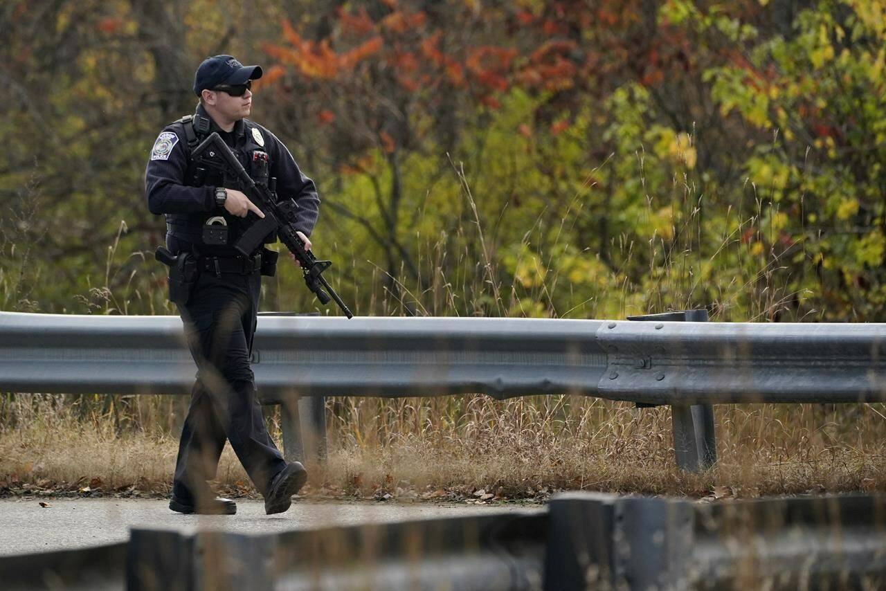 A police officer walks along a rural road during a manhunt for the suspect of Wednesday’s mass shootings, Thursday, Oct. 26, 2023, in Lisbon, Maine. The shootings took place at a restaurant and bowling alley in nearby Lewiston, Maine. THE CANADIAN PRESS/AP-Robert F. Bukaty