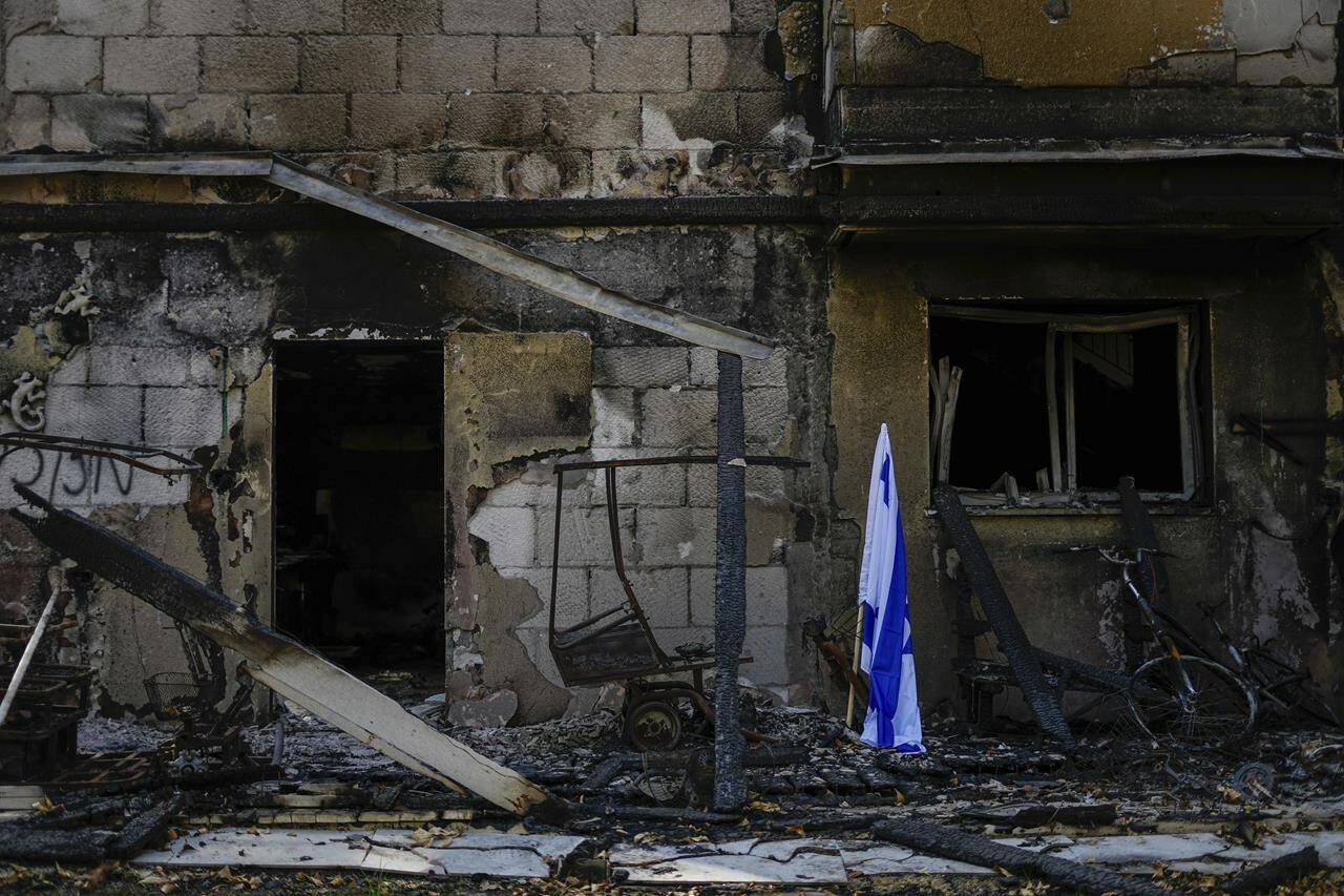 The son of a Canadian woman believed to be among Hamas hostages in Gaza wants the world to push for an end to to the fighting, and he fears Israel’s escalating offensive could end all chance of her surviving. An Israeli flag is placed next to a house destroyed by Hamas militants in Kibbutz Be’eri, Israel, Sunday, Oct. 22, 2023. THE CANADIAN PRESS/AP-Ariel Schalit