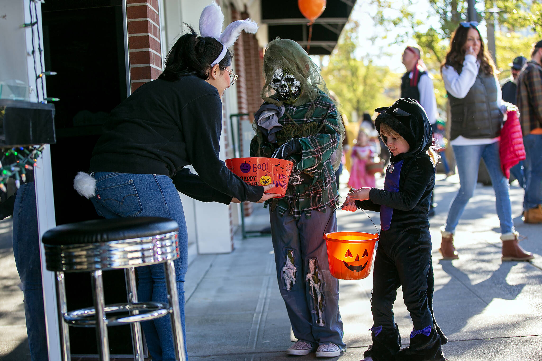 Angus Reid Institute’s latest poll says 54 per cent of Canadians believe there are fewer kids trick-or-treating in their neighbourhood compared to a decade ago. Dinah Zengilou from Botan Ramen n’ Bar hands out candy during Downtown Everett Association’s trick-or-treat event Saturday, Oct. 28, 2023, in Everett, Washington. (Ryan Berry/The Herald)