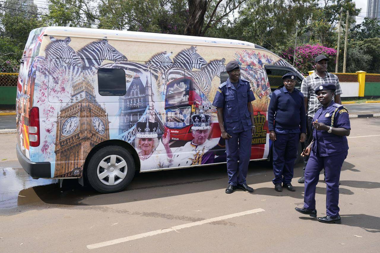 Nairobi county inspectors stand by a matatu adorned with a photo of Britain’s King Charles III and Queen Camilla ahead of their state visit to Kenya, in Nairobi, Kenya, Friday, Oct. 27, 2023. (AP Photo/Khalil Senosi)