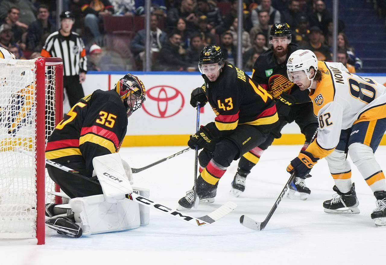 Vancouver Canucks goalie Thatcher Demko (35) stops Nashville Predators’ Tommy Novak (82) as Vancouver’s Quinn Hughes (43) watches during the second period of an NHL hockey game in Vancouver, on Tuesday, October 31, 2023. THE CANADIAN PRESS/Darryl Dyck