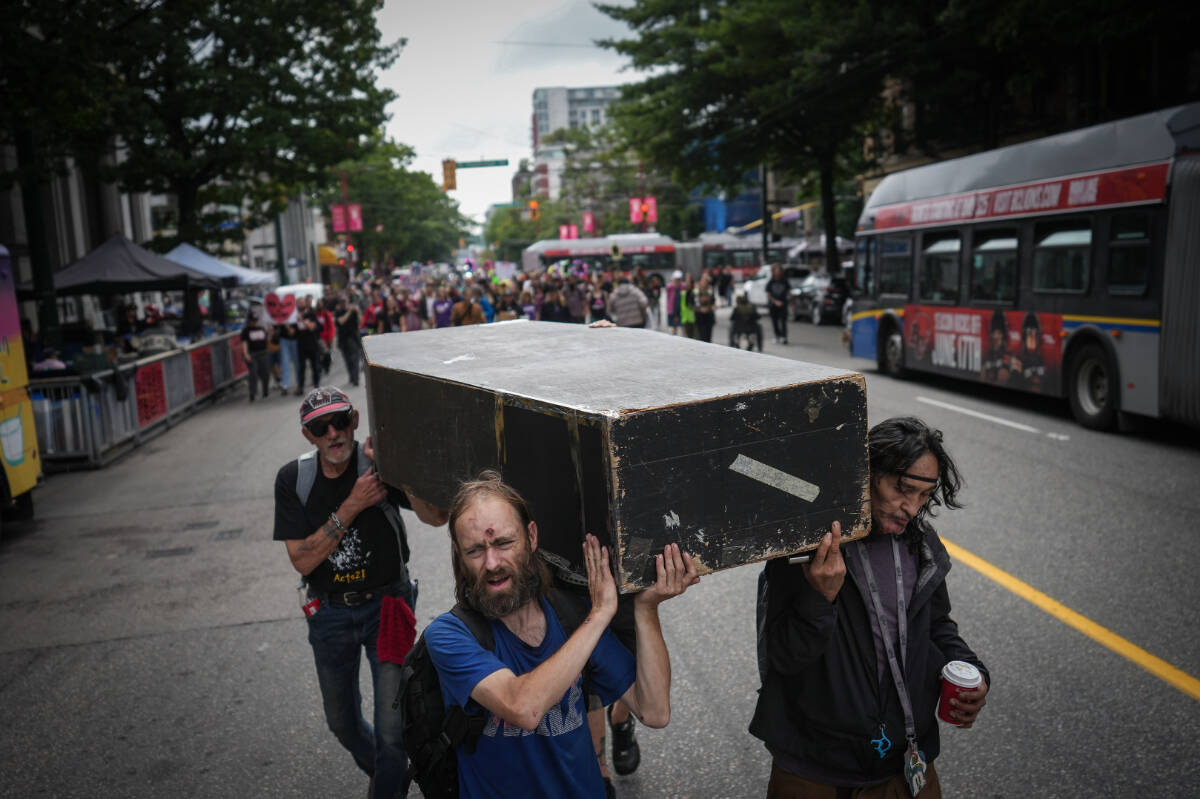 Andrew Leavens, front left, and Carl Gladue, right, carry an empty coffin during a march organized by the Vancouver Area Network of Drug Users (VANDU) to mark International Overdose Awareness Day, in Vancouver, on Thursday, August 31, 2023. THE CANADIAN PRESS/Darryl Dyck