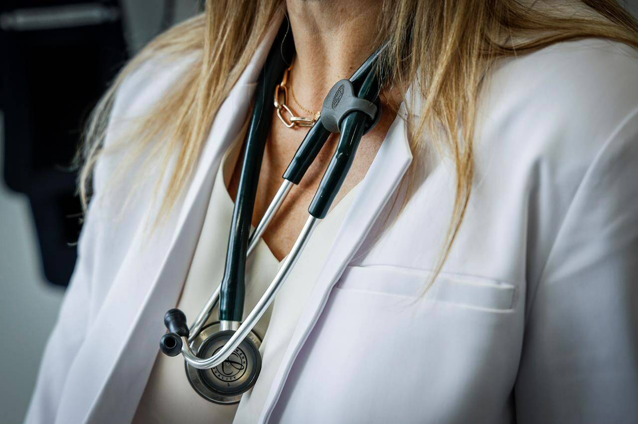 Health spending in Canada is on track to reach $344 billion in 2023, new data from the Canadian Institute for Health Information says. A doctor wears a lab coat and stethoscope in an exam room at a health clinic in Calgary, Alta., Friday, July 14, 2023. THE CANADIAN PRESS/Jeff McIntosh