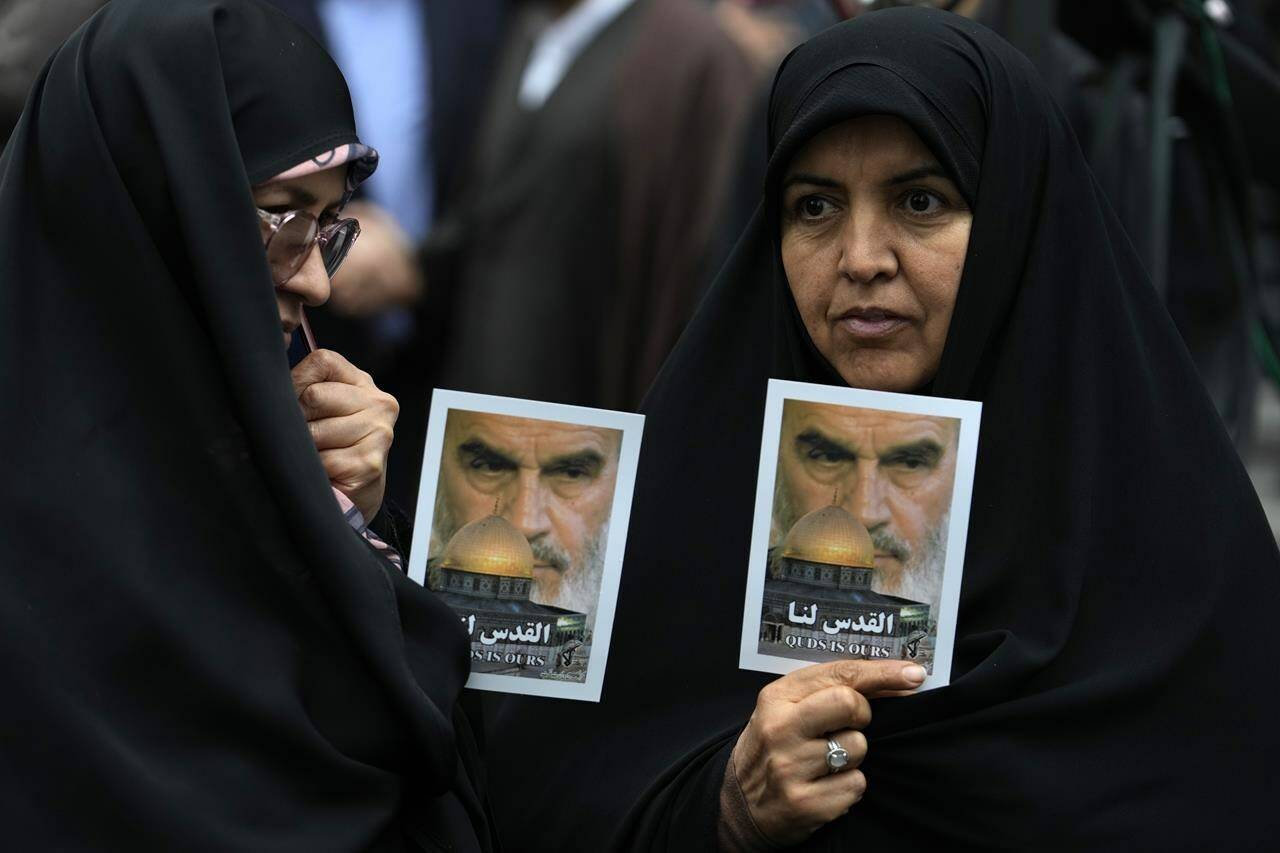 Iranian demonstrators holds posters of the late revolutionary founder Ayatollah Khomeini and Jerusalem’s Dome of the Rock during a rally in front of the former U.S. Embassy in Tehran, Iran, marking 44th anniversary of the seizure of the embassy by militant Iranian students, Saturday, Nov. 4, 2023. (AP Photo/Vahid Salemi)