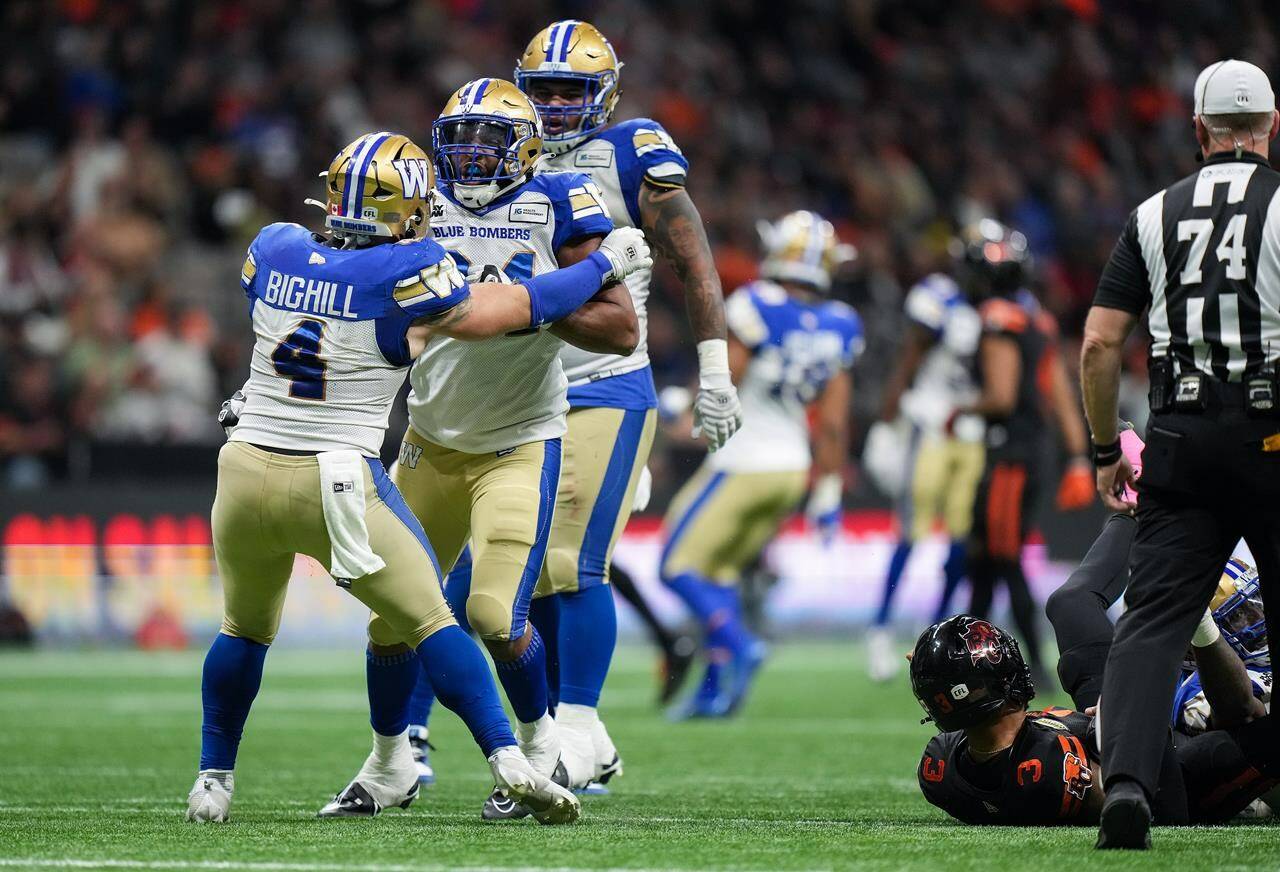 Winnipeg Blue Bombers’ Adam Bighill, front left to right, Jackson Jeffcoat and Ricky Walker celebrate after Jeffcoat sacked B.C. Lions quarterback Vernon Adams Jr., lower right, during the first half of a CFL football game, in Vancouver, on Friday, Oct. 6, 2023. THE CANADIAN PRESS/Darryl Dyck