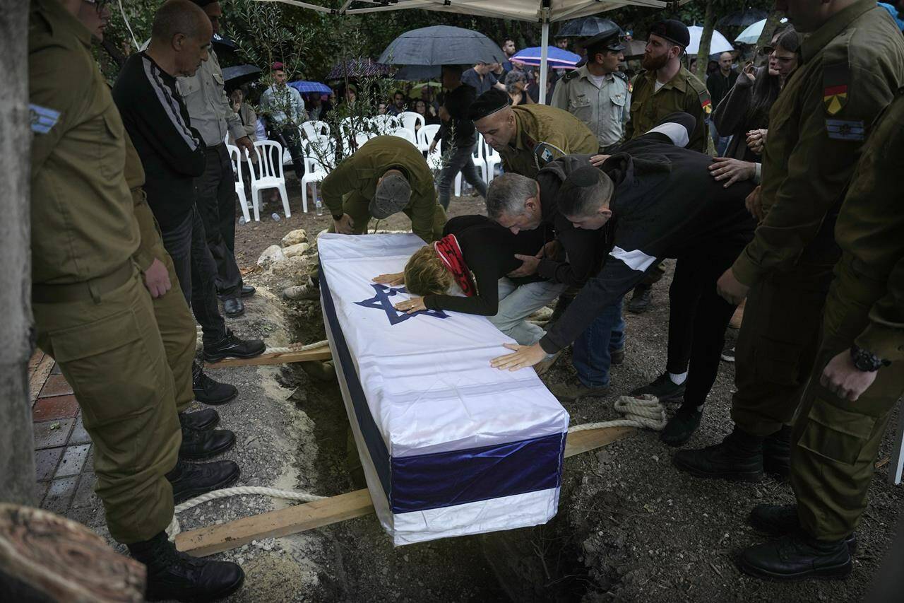 Adva Rozenblit mourns over the coffin of her son staff Sgt. Gilad Rozenblit , 21, in Kibbutz Ginegar, northern Israel, Sunday Nov. 12, 2023. He was killed during a ground operation in the Gaza Strip.(AP Photo/Ariel Schalit)