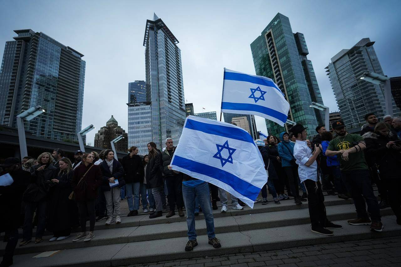 People hold Israeli flags during a vigil organized by the Jewish Federation of Greater Vancouver in support of those killed in Israel, in Vancouver, on Tuesday, October 10, 2023. Canadian Jewish organizations are calling on the Liberal government to remove what they see as barriers to enforcing a relatively new Criminal Code provision against Holocaust denialism amid a rise in antisemitism. THE CANADIAN PRESS/Darryl Dyck