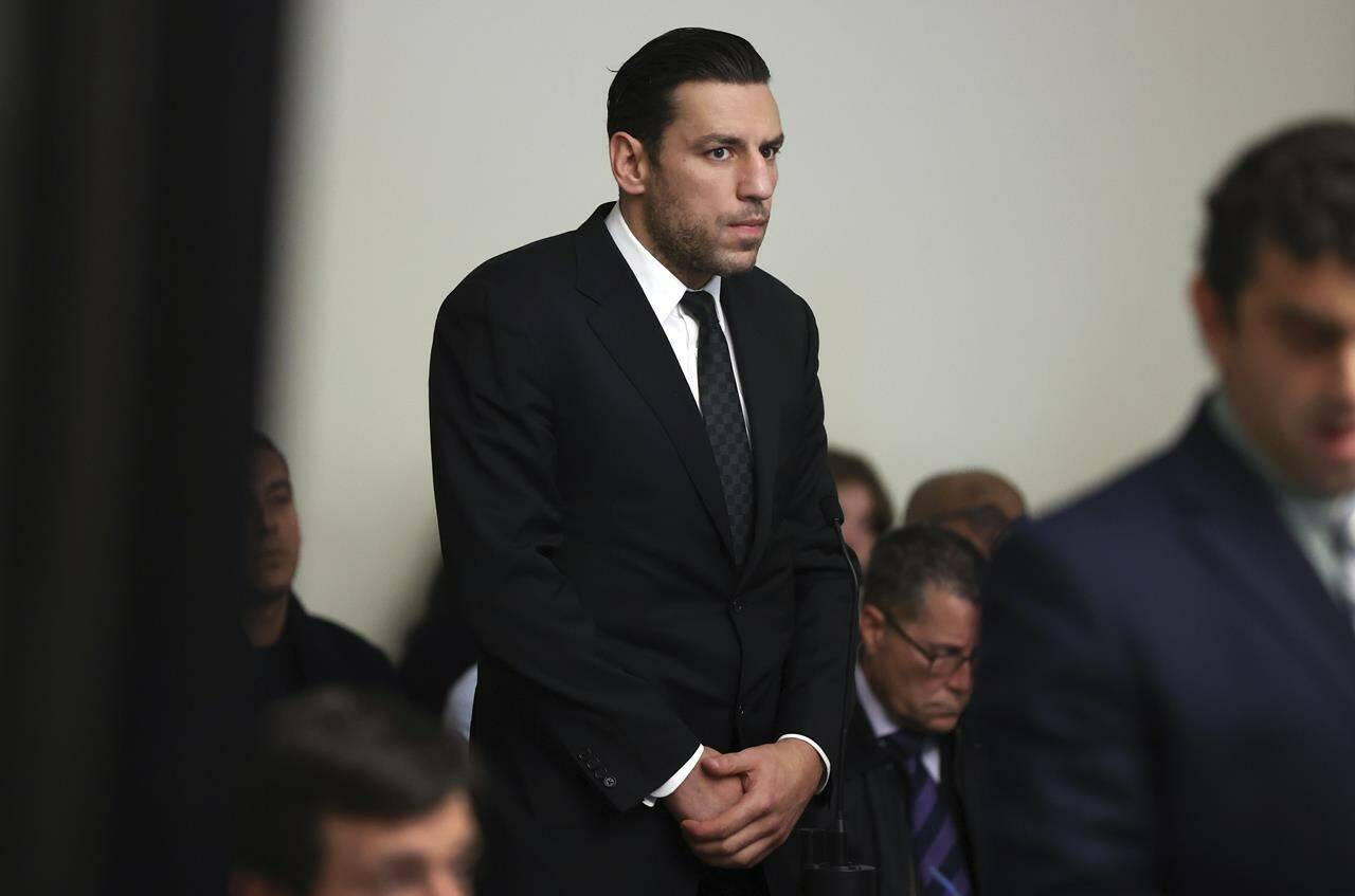 Boston Bruins forward Milan Lucic, center, stands during his arraignment Tuesday, Nov. 21, 2023, in Boston Municipal Court, in Boston, on an assault charge in connection with his arrest over the weekend after his wife called police to their home and said he tried to choke her. Lucic has been released on personal recognizance bail after pleading not guilty to assaulting his wife. (Jonathan Wiggs/The Boston Globe via AP, Pool)