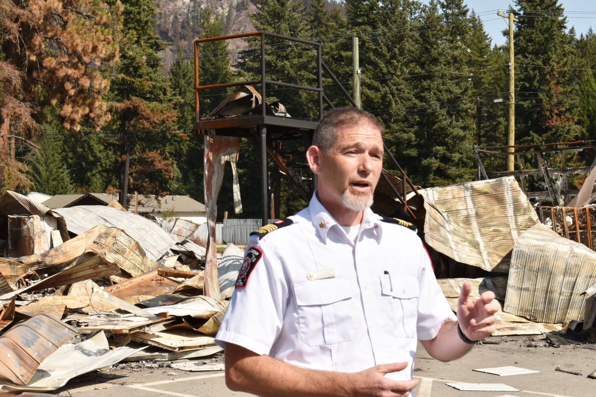 Sean Coubrough, CSRD deputy regional fire chief, stands in front of the remains of the Scotch Creek/Lee Creek fire hall after the Bush Creek East wildfire burned through the area. (File photo)