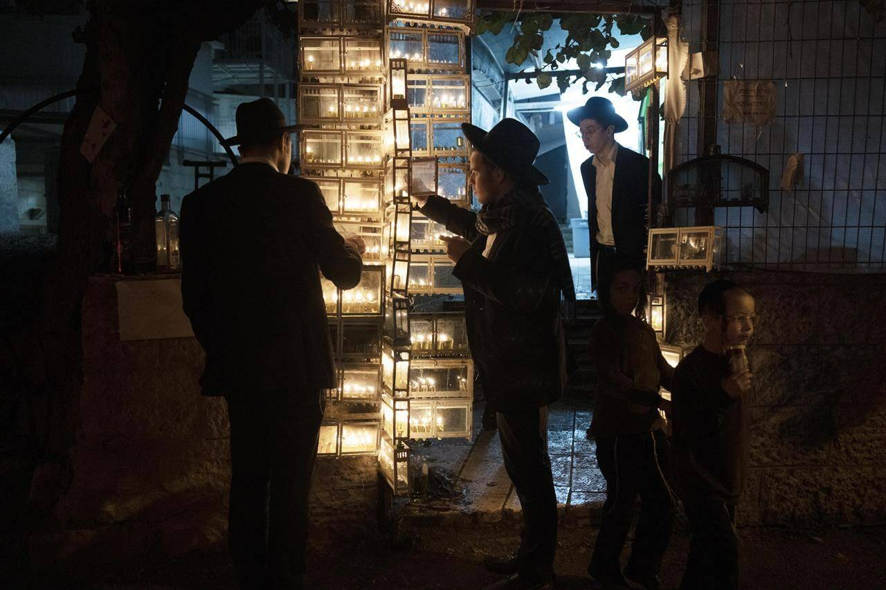 Ultra-Orthodox Jewish seminary students light candles on the fifth night of Hanukkah in the Mea Shearim neighbourhood of Jerusalem, Thursday, Dec. 22, 2022. Hanukkah, also known as the Festival of Lights, is an eight-day festival that celebrates the victory of Jewish fighters over the ancient Greeks and the rededication of the Jewish Temple. THE CANADIAN PRESS/AP-Maya Alleruzzo