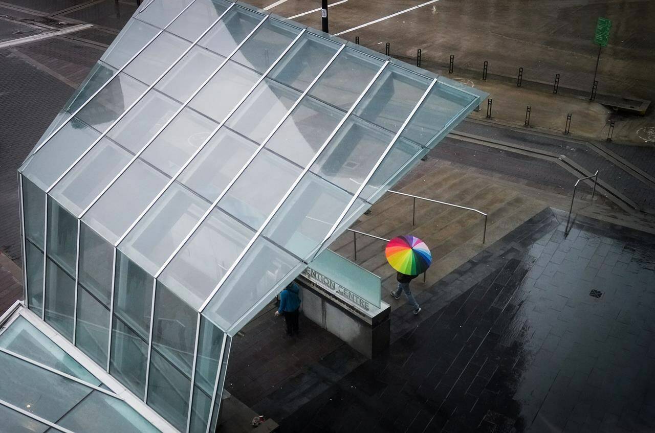 Parts of southwestern British Columbia remain under a rainfall warning as a potent atmospheric river made landfall along the province’s coast Monday. A pedestrian uses an umbrella to shield themselves from the rain while walking in downtown Vancouver, on Tuesday, February 7, 2023. THE CANADIAN PRESS/Darryl Dyck