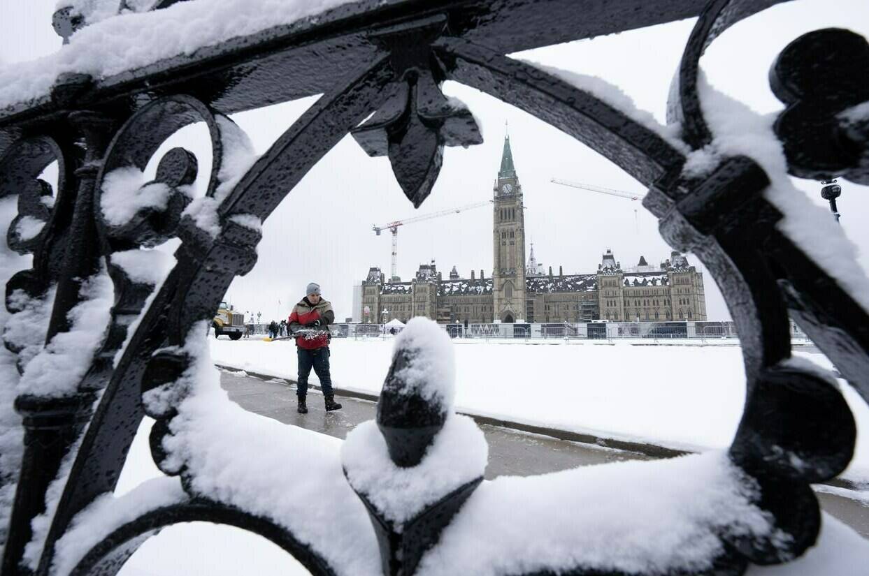 A worker prepares a pathway on Parliament Hill following a snow fall, in Ottawa, Monday, Dec. 4, 2023. The federal government should spend more on health care, a housing strategy, and inflation and cost of living initiatives—and freeze or reduce spending elsewhere, according to a new poll.THE CANADIAN PRESS/Adrian Wyld