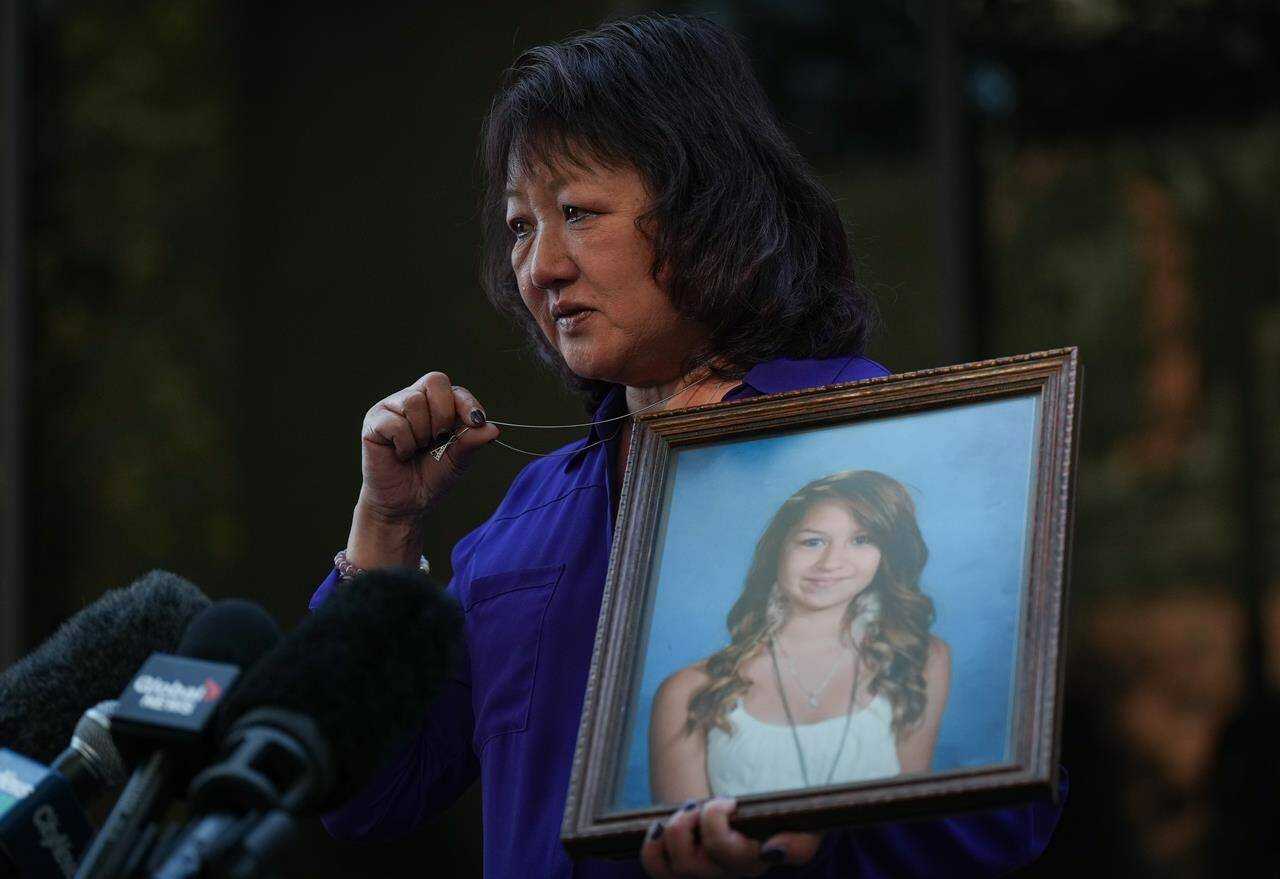 Carol Todd holds a photo of her late teenage daughter Amanda Todd, who died by suicide in 2012, and the necklace she was wearing in the school photo as she speaks outside B.C. Supreme Court after sentencing for the Dutch man who was accused of extorting and harassing her daughter, in New Westminster, B.C., on Friday, Oct. 14, 2022. THE CANADIAN PRESS/Darryl Dyck