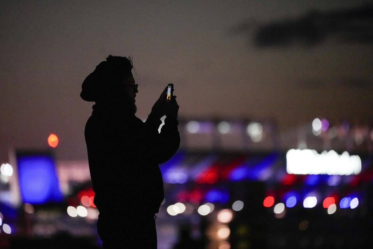 Canadian wireless companies collectively spent about $2.1 billion on chunks of 5G bandwidth in the federal government’s most recent spectrum auction. A man uses a cell phone to capture images at Federal Hill Park, Wednesday, Jan. 4, 2023, in Baltimore. THE CANADIAN PRESS/AP-Julio Cortez