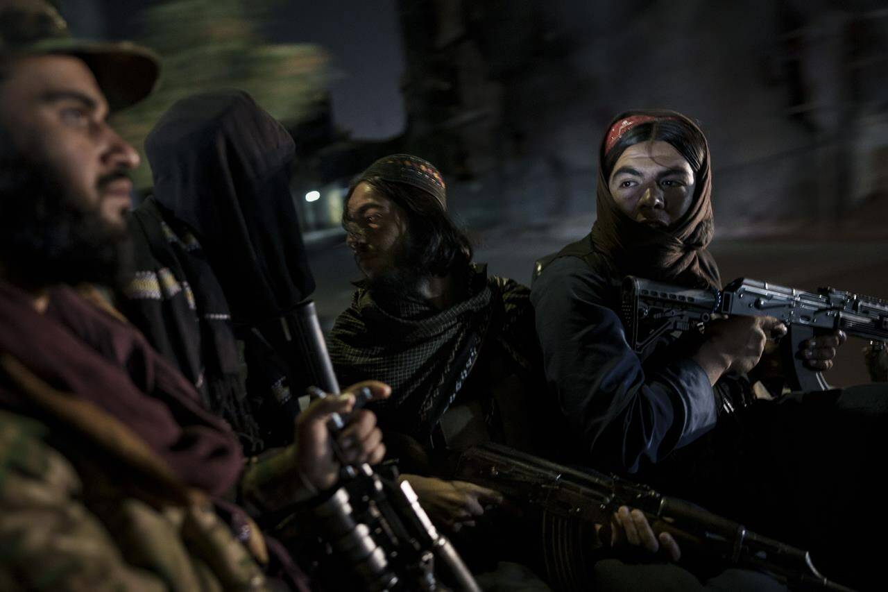 FILE - Taliban fighters ride in the back of a vehicle during a night patrol in Kabul, Afghanistan, on Sept. 12, 2021. Taliban officials are sending Afghan women to prison to protect them from gender-based violence, according to a U.N. report published Thursday, Dec. 14, 2023. (AP Photo/Felipe Dana, File)