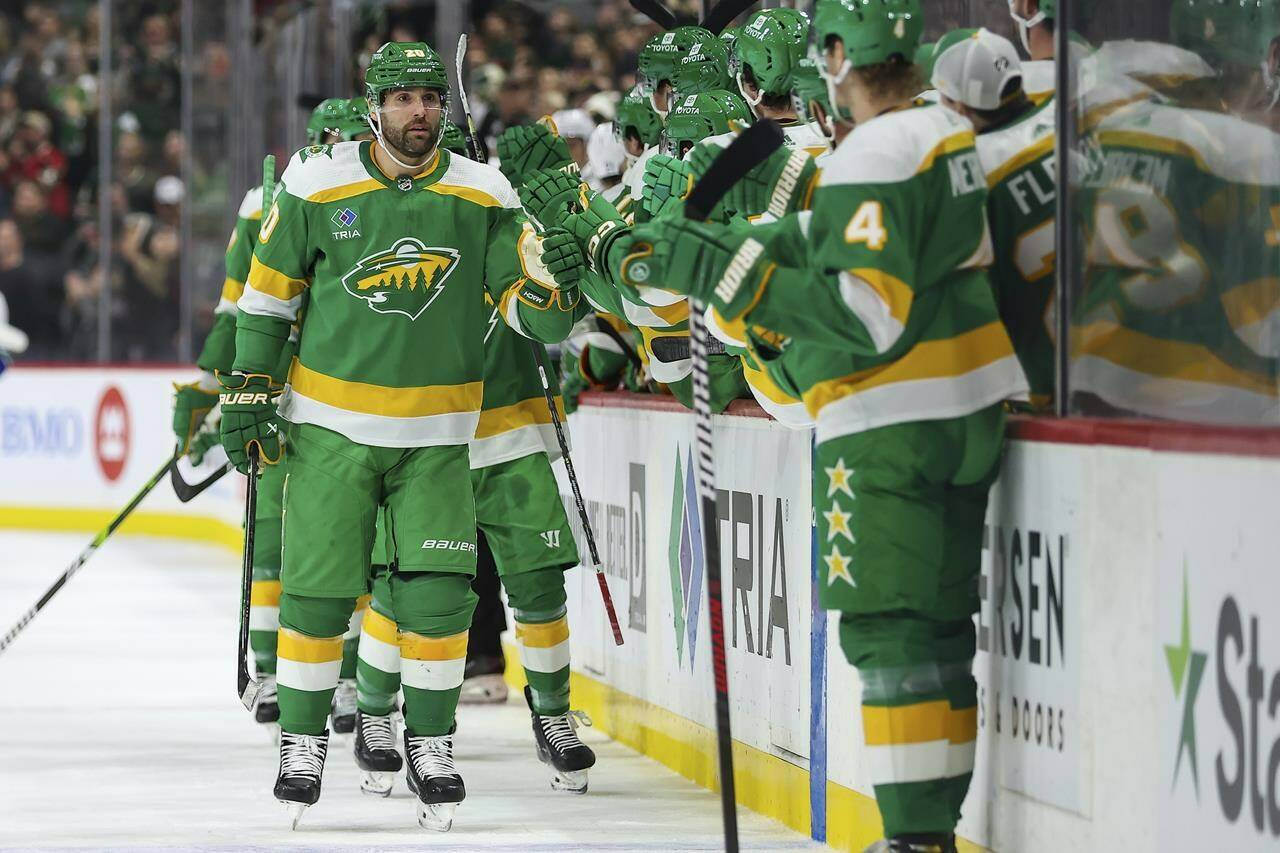 Minnesota Wild left wing Pat Maroon (20) is congratulated on his assist to center Frederick Gaudreau (89) which marks his 300th career point during the first period of an NHL hockey game against the Vancouver Canucks, Saturday, Dec. 16, 2023, in St Paul, Minn. (AP Photo/Matt Krohn)